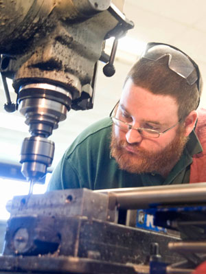 Machinist Kirk Johnson of Cortland Custom Machining Technology lines up a drill press while making grooves in a fabricated part Monday.